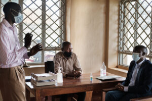 Robert in an office with two other man, one of them is using sign language to communicate
