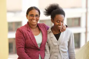 Mentor and mentee pose together in the We Can Work space; two women smile, one in a magenta blazer and the other in a gray shirt, conveying disability inclusion.